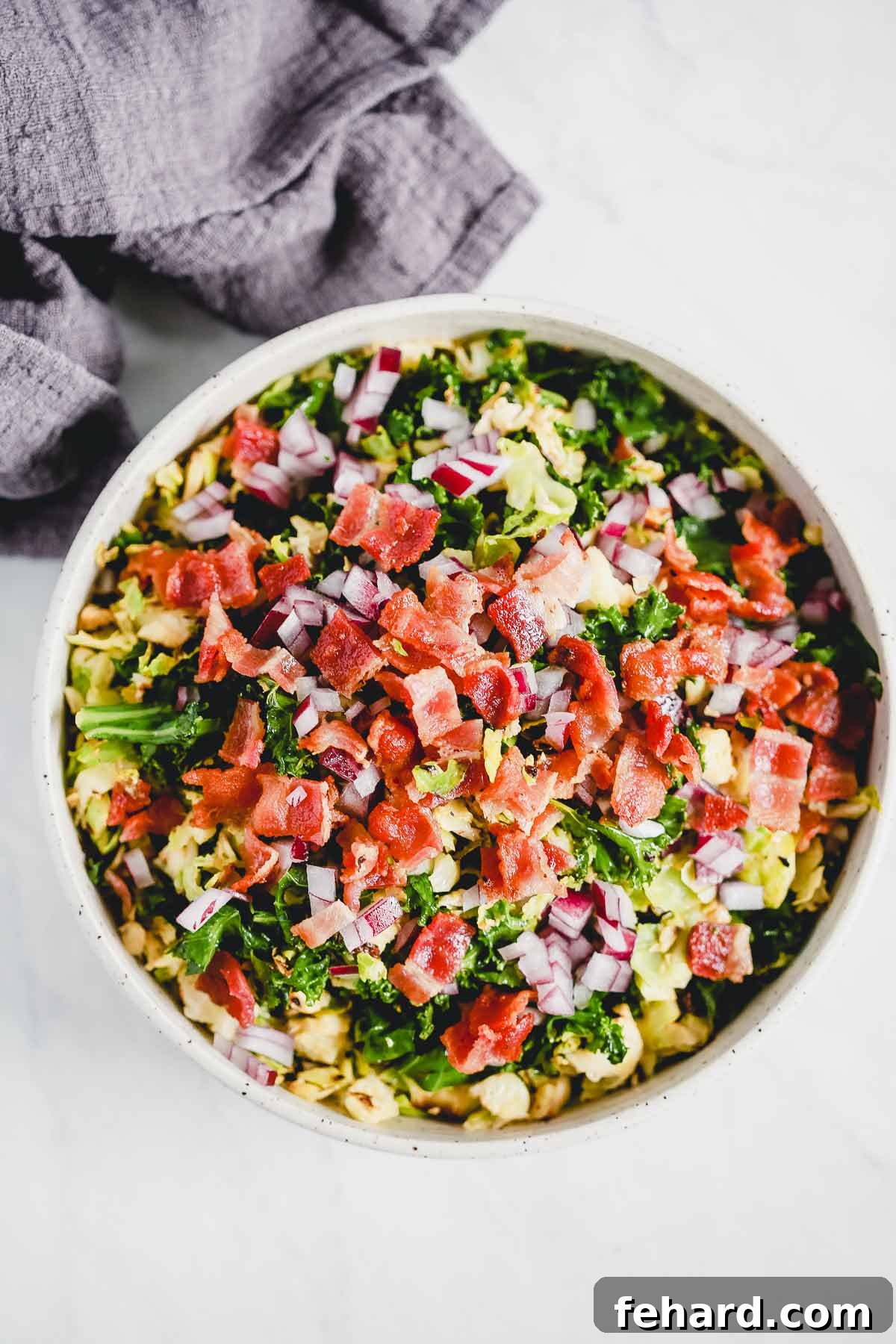 A large serving bowl filled with a fresh Brussels Sprouts Bacon Salad, ready to be enjoyed.