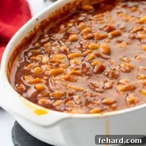 Saucy brown sugar baked beans in large white casserole dish.