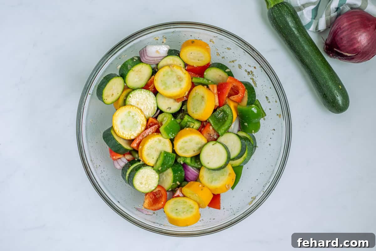 A large mixing bowl filled with colorful bell peppers, onions, and summer squash, all generously tossed with a savory marinade, ready for threading onto skewers.