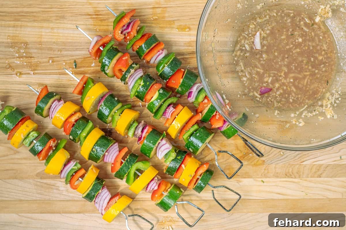 Prepared skewers showcasing an appealing alternating pattern of red bell peppers, onions, zucchini, and yellow squash, ready for the grill.