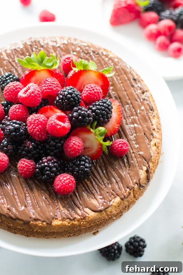 An overhead image of a beautifully garnished almond cake with fresh berries, sitting elegantly on a cake stand, ready to be enjoyed.