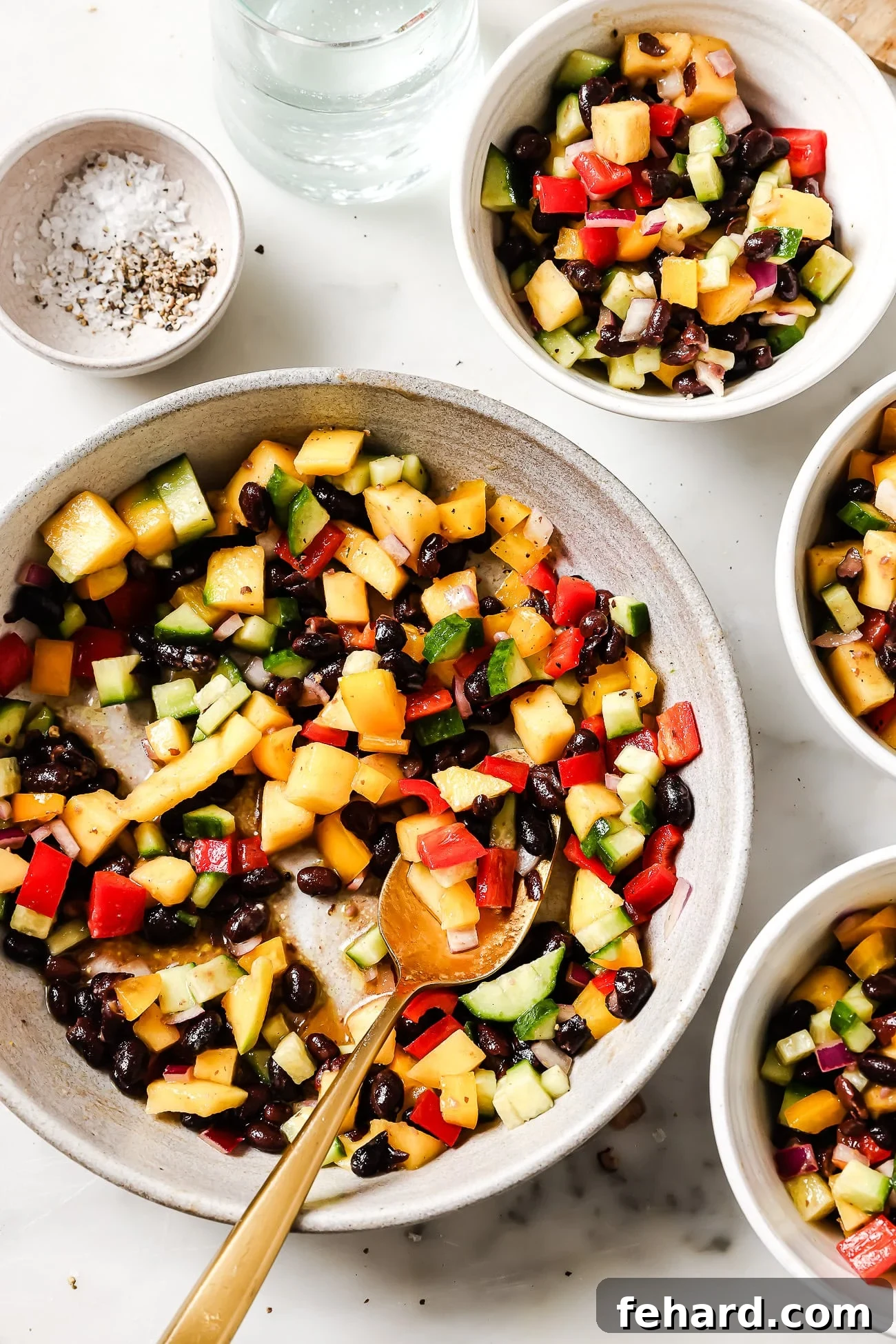 Assortment of black bean mango salad in various serving bowls, highlighting its colorful presentation.