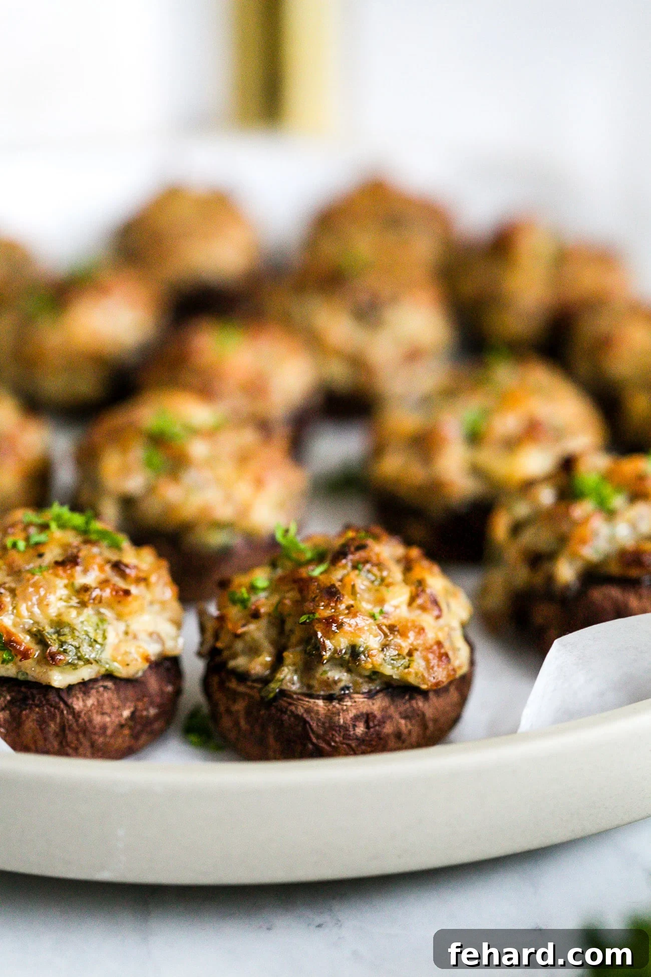 Closeup of a golden-brown sausage stuffed mushroom, perfectly baked and garnished.