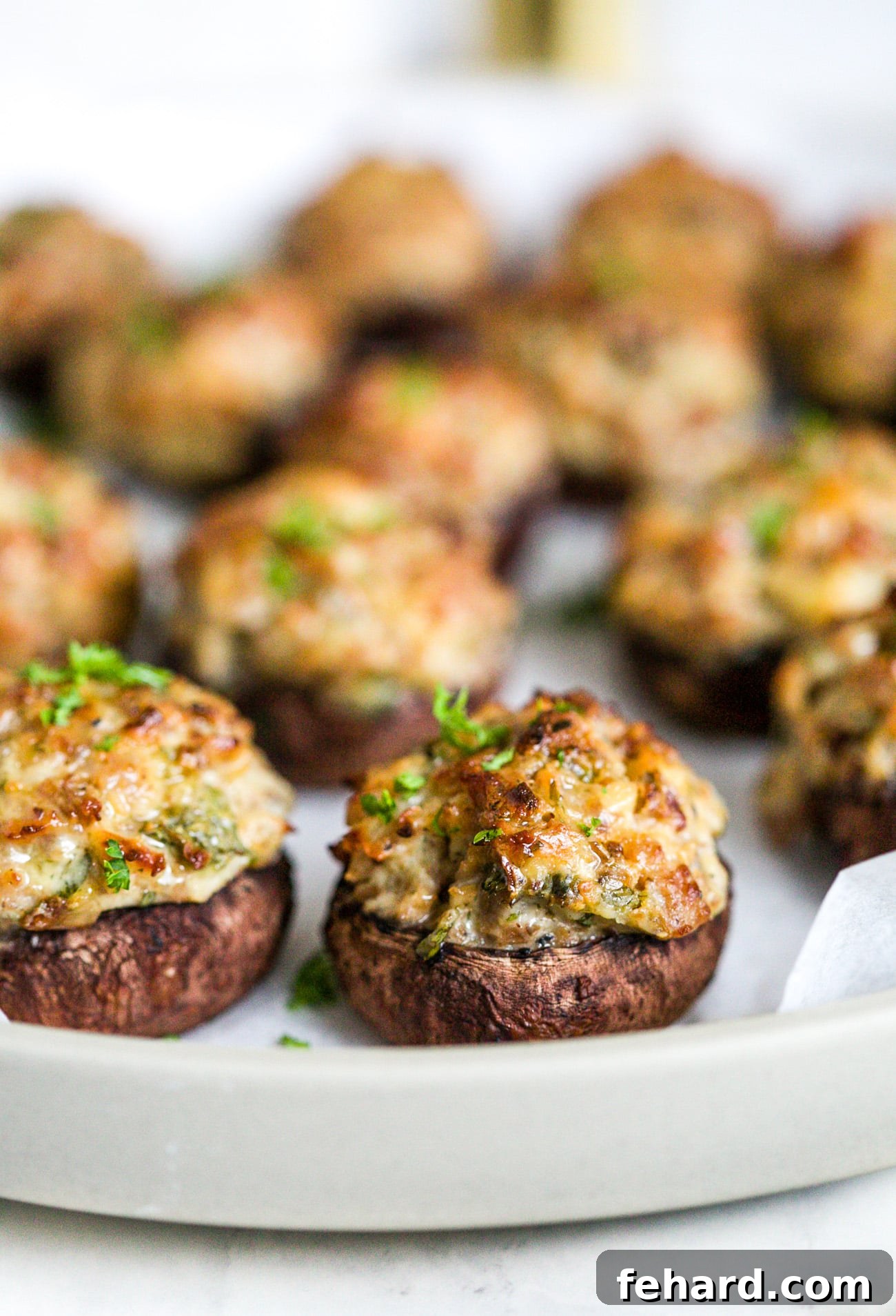 Closeup of a finished sausage stuffed mushroom, beautifully baked and garnished, ready to be served.