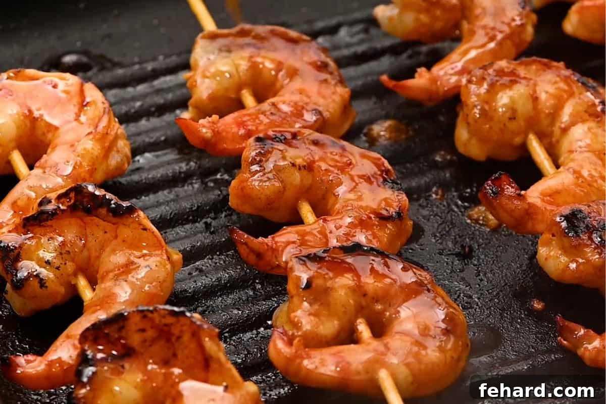 Delicious honey garlic shrimp skewers grilling on a grill pan, coated in a rich glaze and perfectly seared.