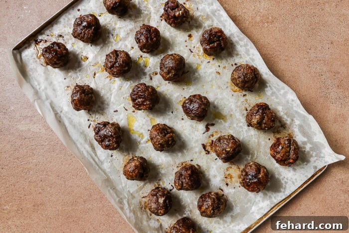 Irresistible Party Meatballs 7 baked meatballs on a baking sheet.