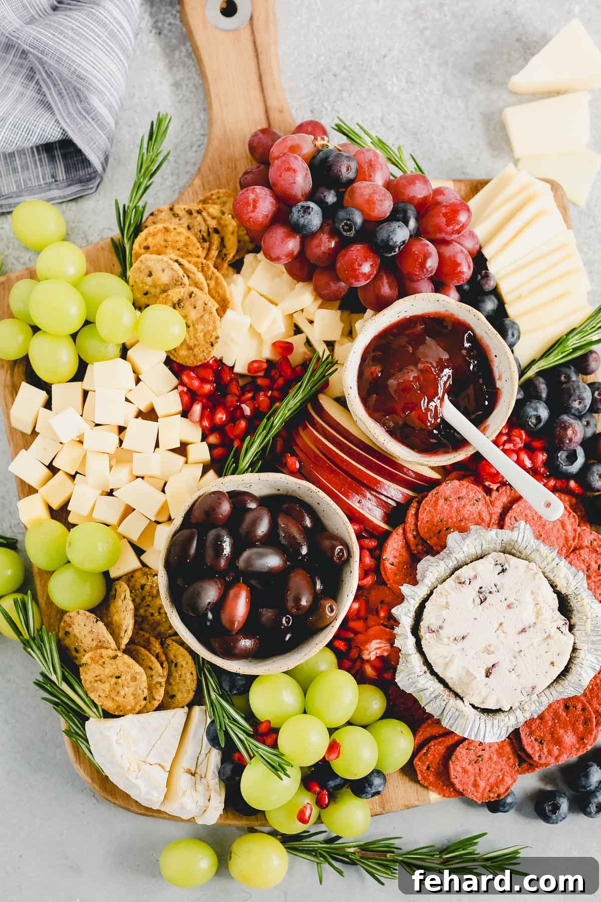 Overhead close-up view of a Holiday Cheese Board, highlighting the vibrant colors and diverse textures of the ingredients.