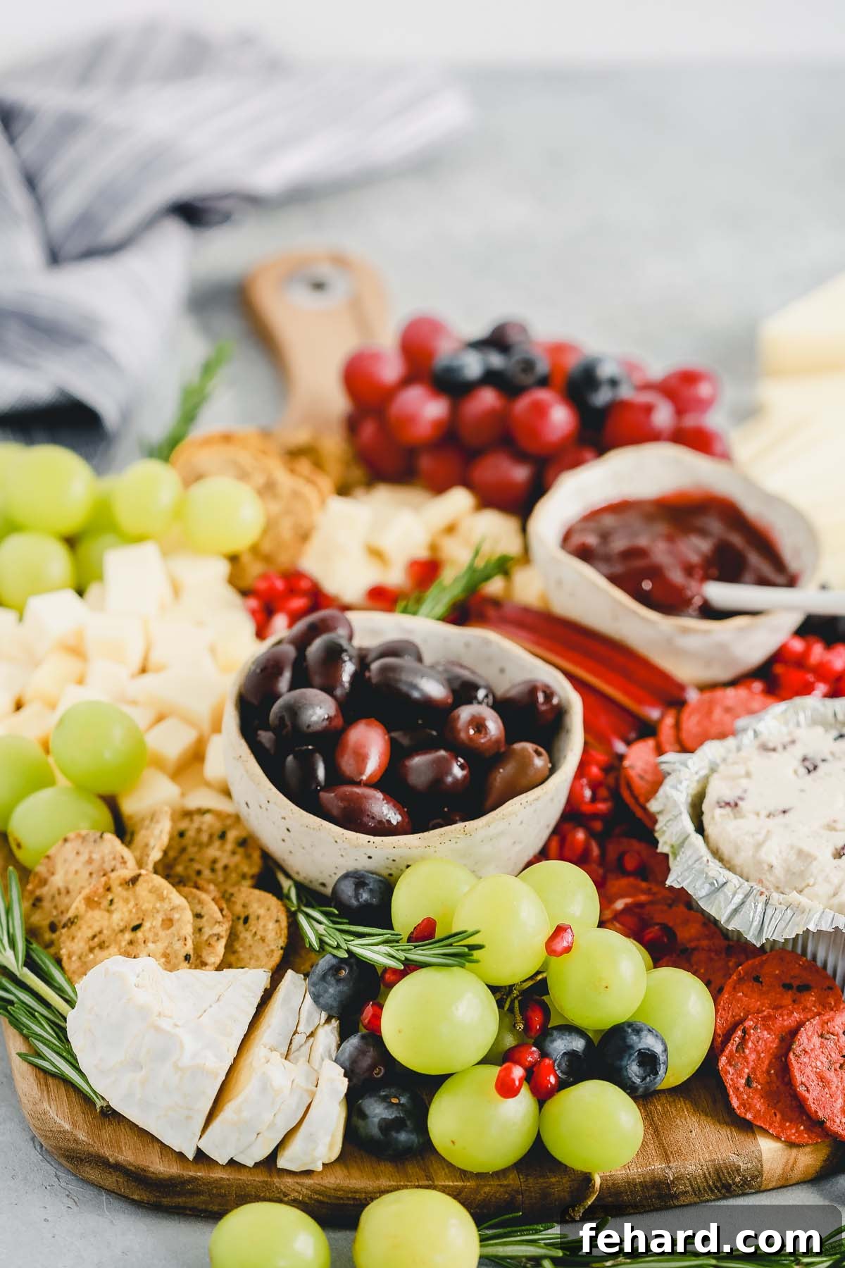 Close-up of a festive Holiday Cheese Board, highlighting the texture of the cheeses and fresh garnishes.