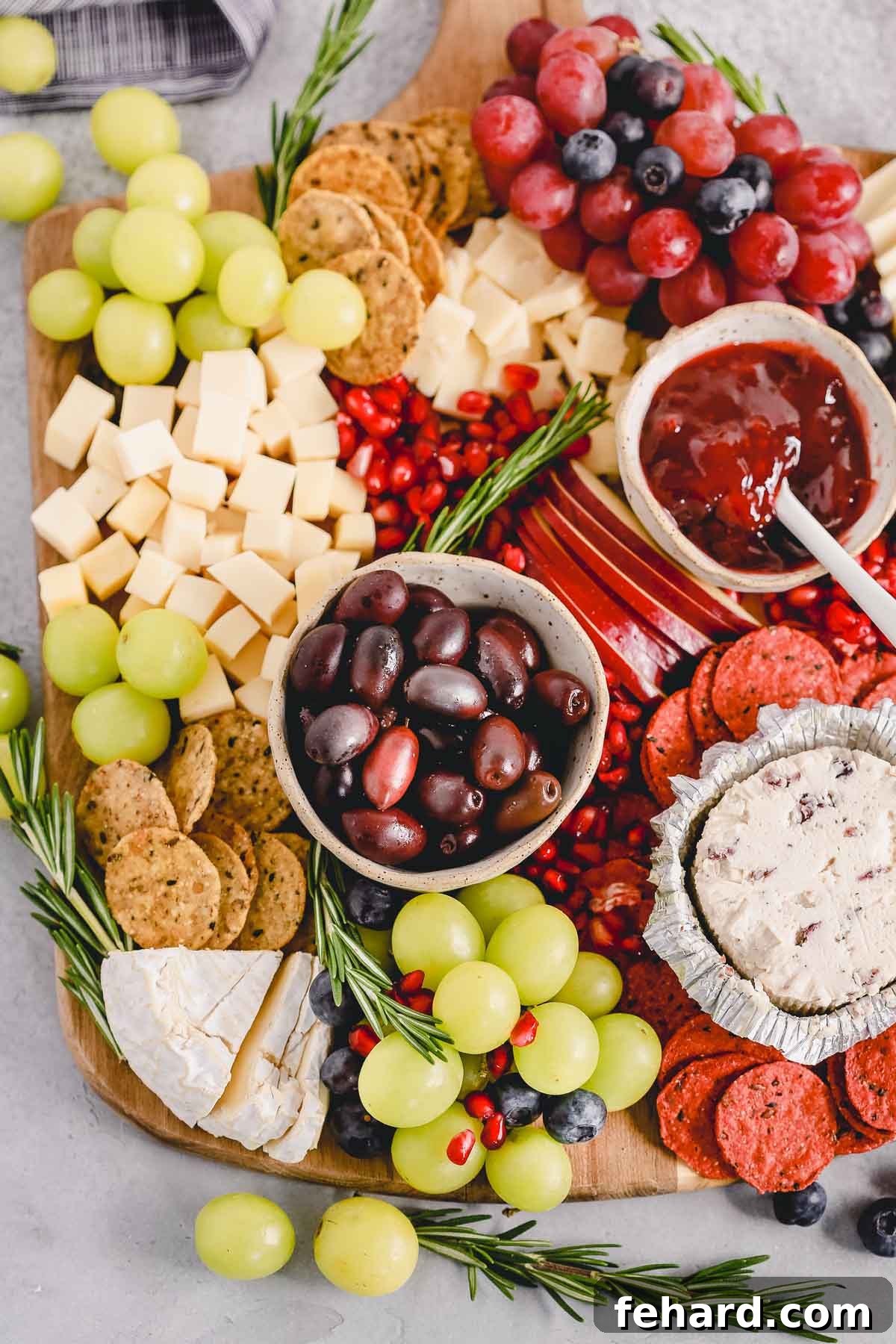 Overhead view of a richly assembled Holiday Cheese Board, featuring an abundance of ingredients and garnishes.