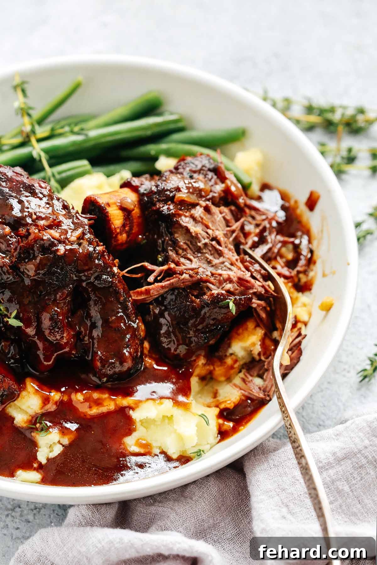 Close-up shot of tender, braised beef short ribs with a rich sauce.