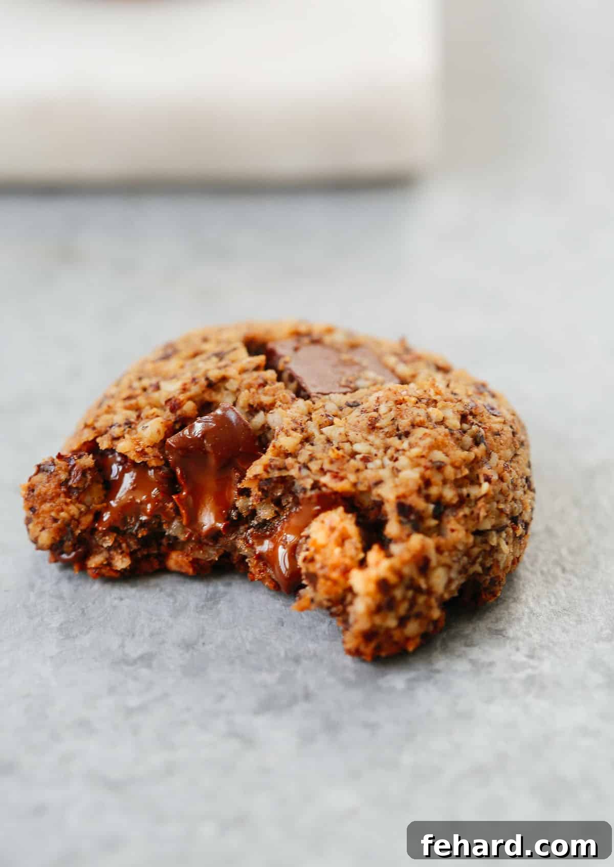 A delicious Chocolate Chunk Hazelnut Cookie with a bite taken out of it, showcasing its soft interior and melted chocolate chunks.
