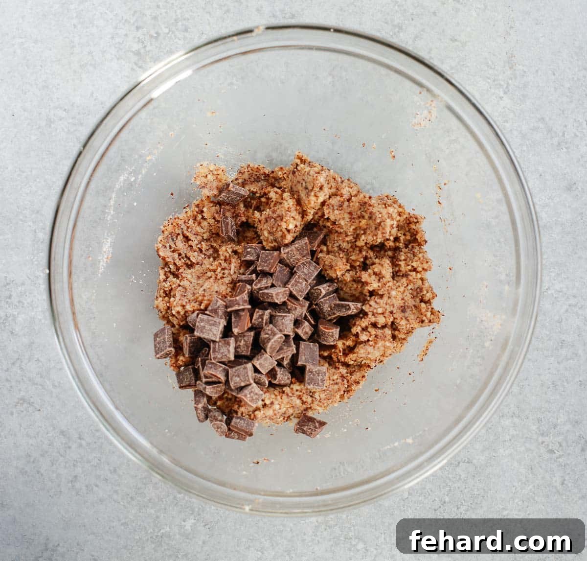 A glass bowl filled with rich cookie dough generously mixed with dark chocolate chunks.