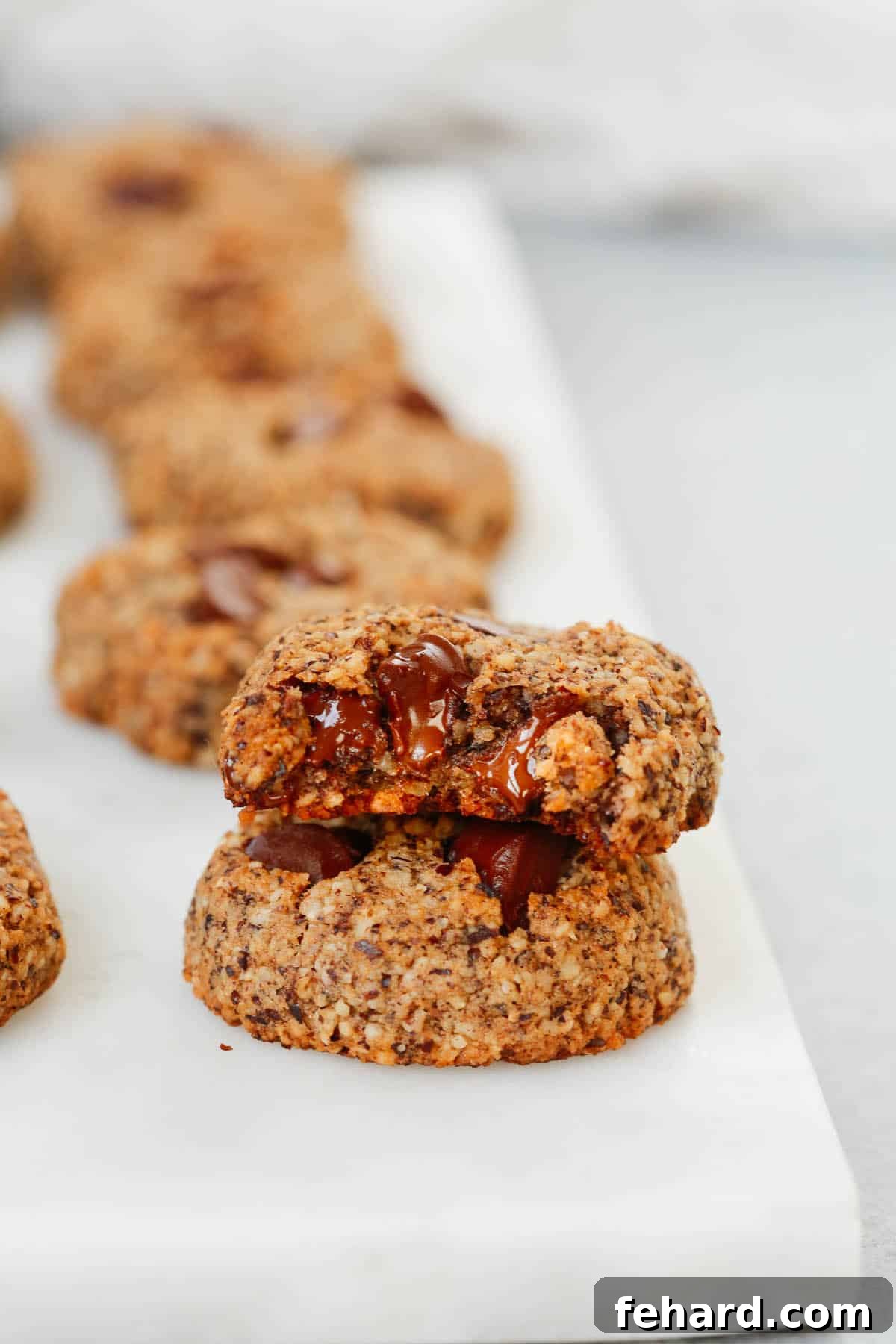 Two perfectly baked Chocolate Chunk Hazelnut Cookies stacked on a elegant marble serving platter, highlighting their inviting texture.