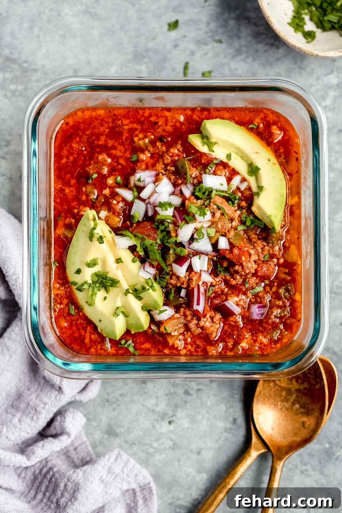 Ultimate Instant Pot Keto Chili 5 glass container holding one serving of chili with avocado slices and onions
