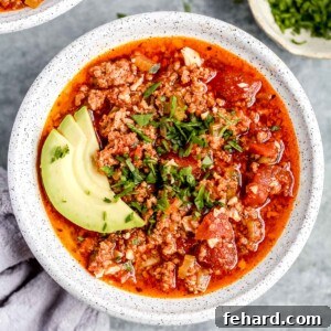 overhead view of a full white bowl of keto chili with avocado slices on top