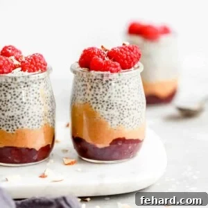 chia seed pudding topped with raspberries in small glass jars