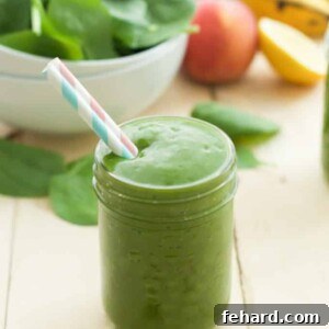 close up of a green smoothie in a mason jar with a straw