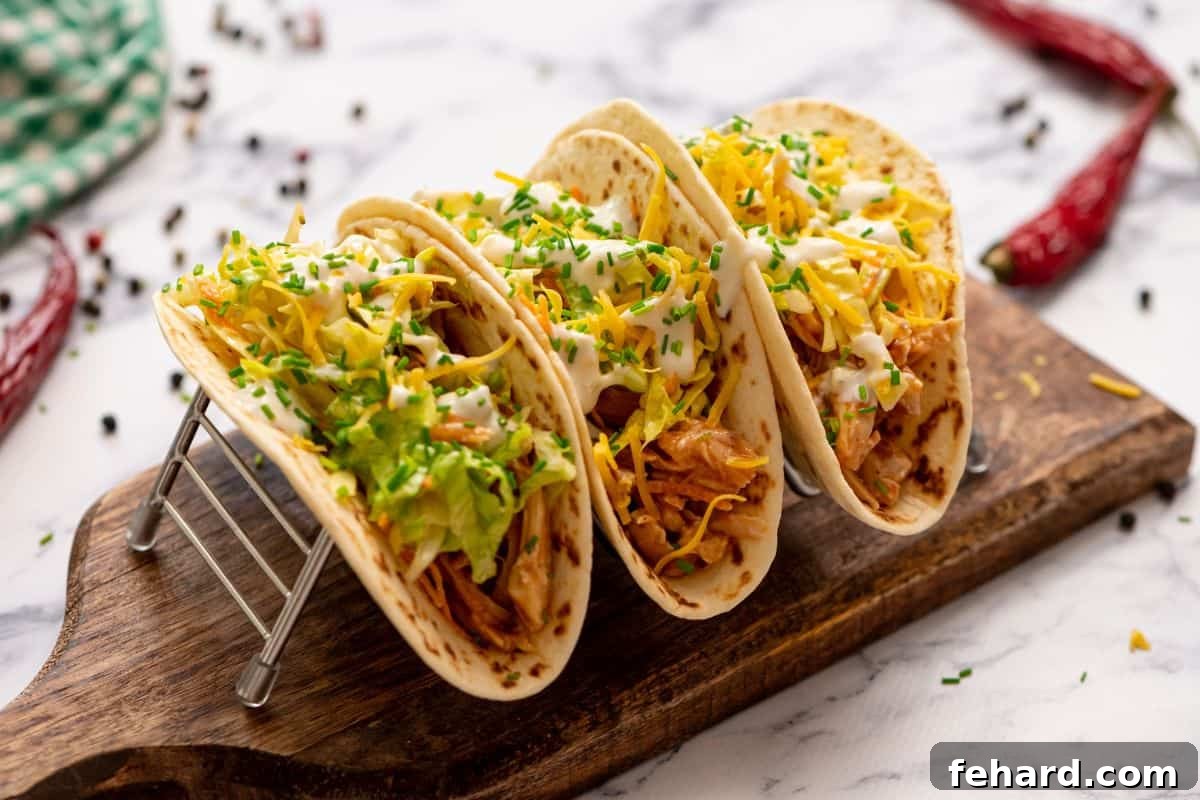Assembled Easy Buffalo Chicken Tacos 3 assembled buffalo chicken tacos on flour tortillas.
