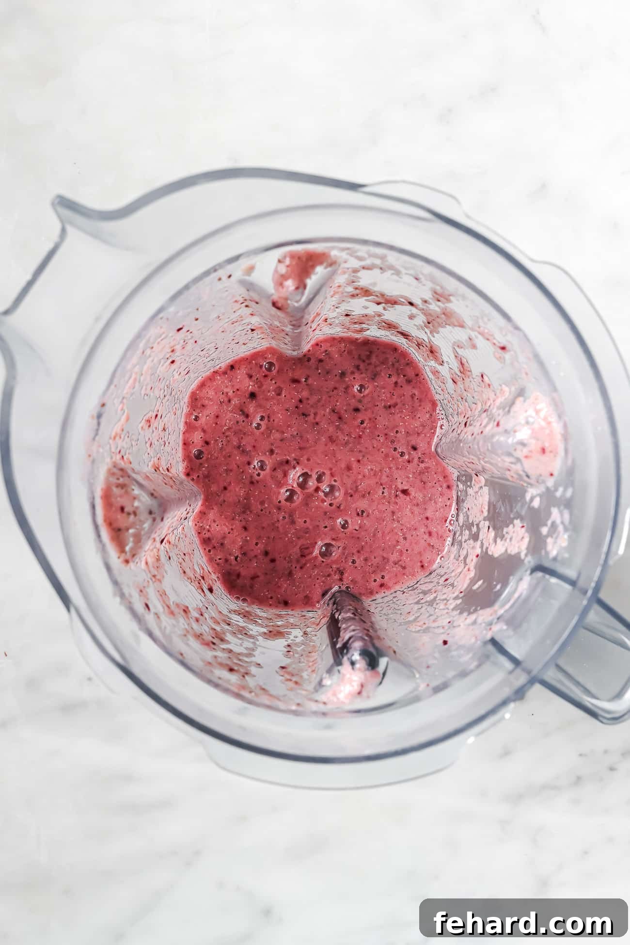 Overhead view of a cherry smoothie in a blender. 