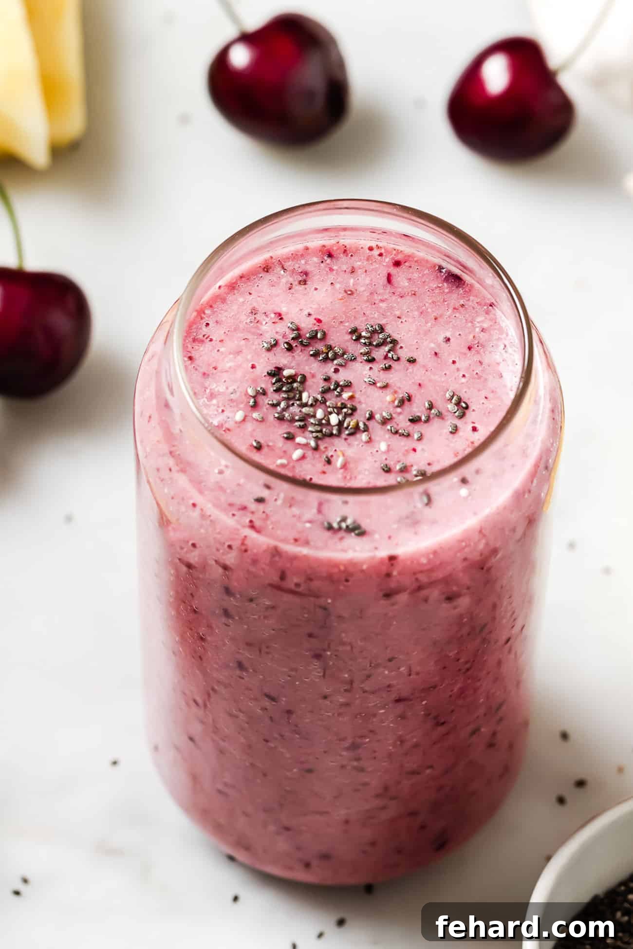 Cherry smoothie in a glass cup garnished with chia seeds.