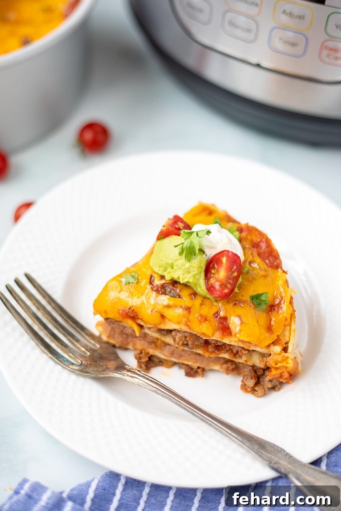 A perfectly sliced piece of Instant Pot Mexican Lasagna on a white plate, with the Instant Pot visible in the soft background.