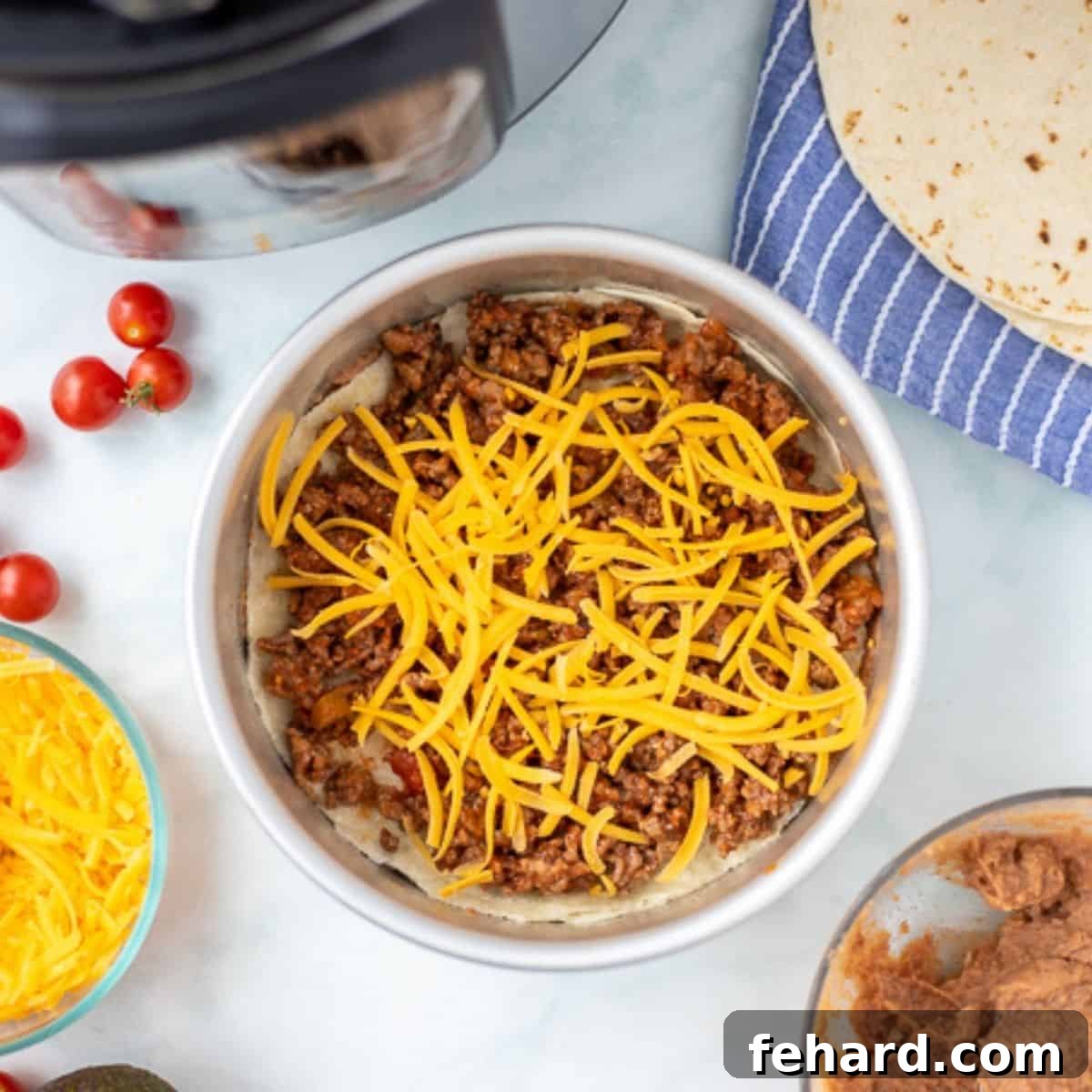 A layer of taco meat and cheese meticulously spread in a cake pan, part of the taco pie assembly.