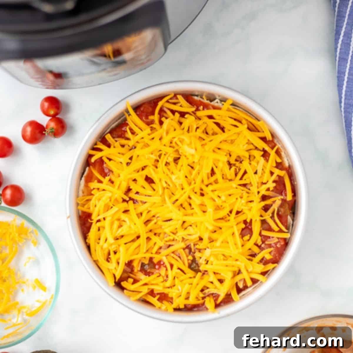 The fully assembled Taco Lasagna in a cake pan, sitting next to an Instant Pot, ready for cooking.