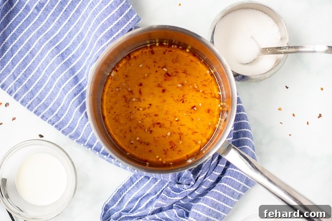 Sweet chili sauce simmering gently in a saucepan, showcasing its rich red color and smooth texture.