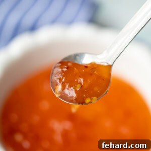 A spoonful of homemade sweet chili sauce, glossy and vibrant, ready to be enjoyed.