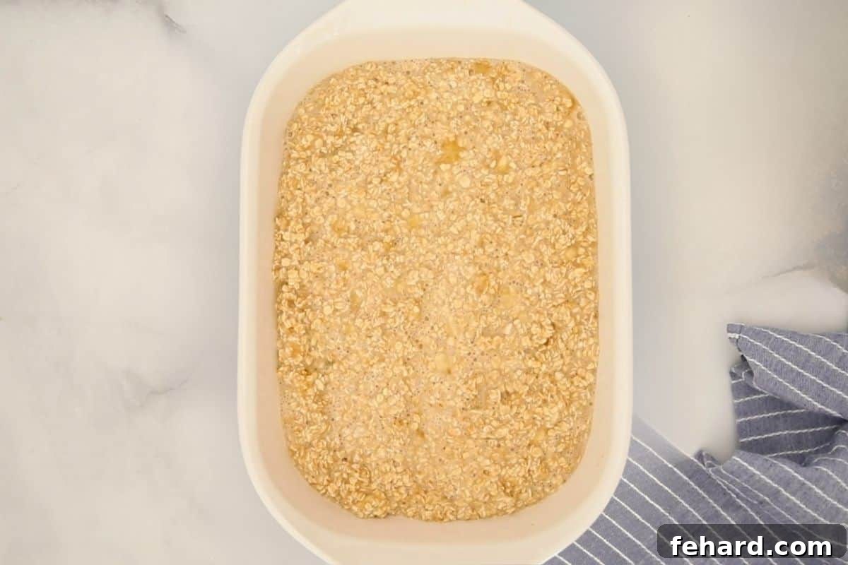 A white baking dish holds the perfectly mixed, unbaked combination of mashed bananas and oats, poised and ready to be placed into the oven for a wholesome, comforting breakfast.