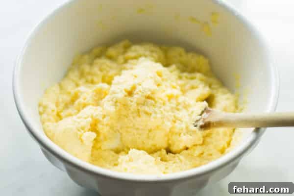 Creamy Ricotta Cheese Mixture for Zucchini Casserole Ricotta cheese mixture in a bowl with a spoon, showing the creamy texture before layering.
