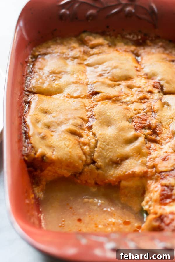 Baked Zucchini Casserole with Ricotta and Parmesan Zucchini casserole in a red baking dish with a slice cut out, ready to serve.