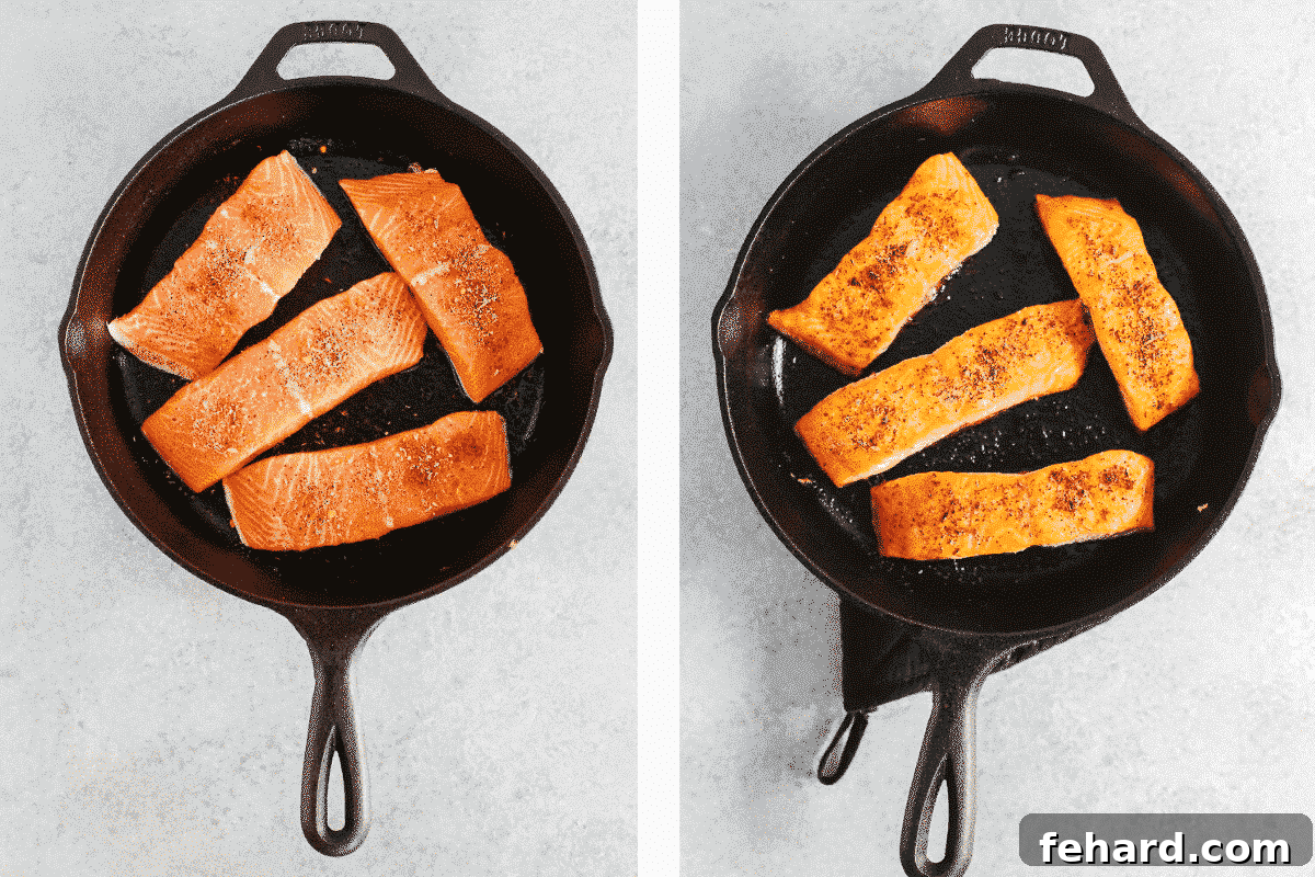 Three salmon fillets searing skin-side down in a hot cast-iron pan, seasoned with herbs and spices.