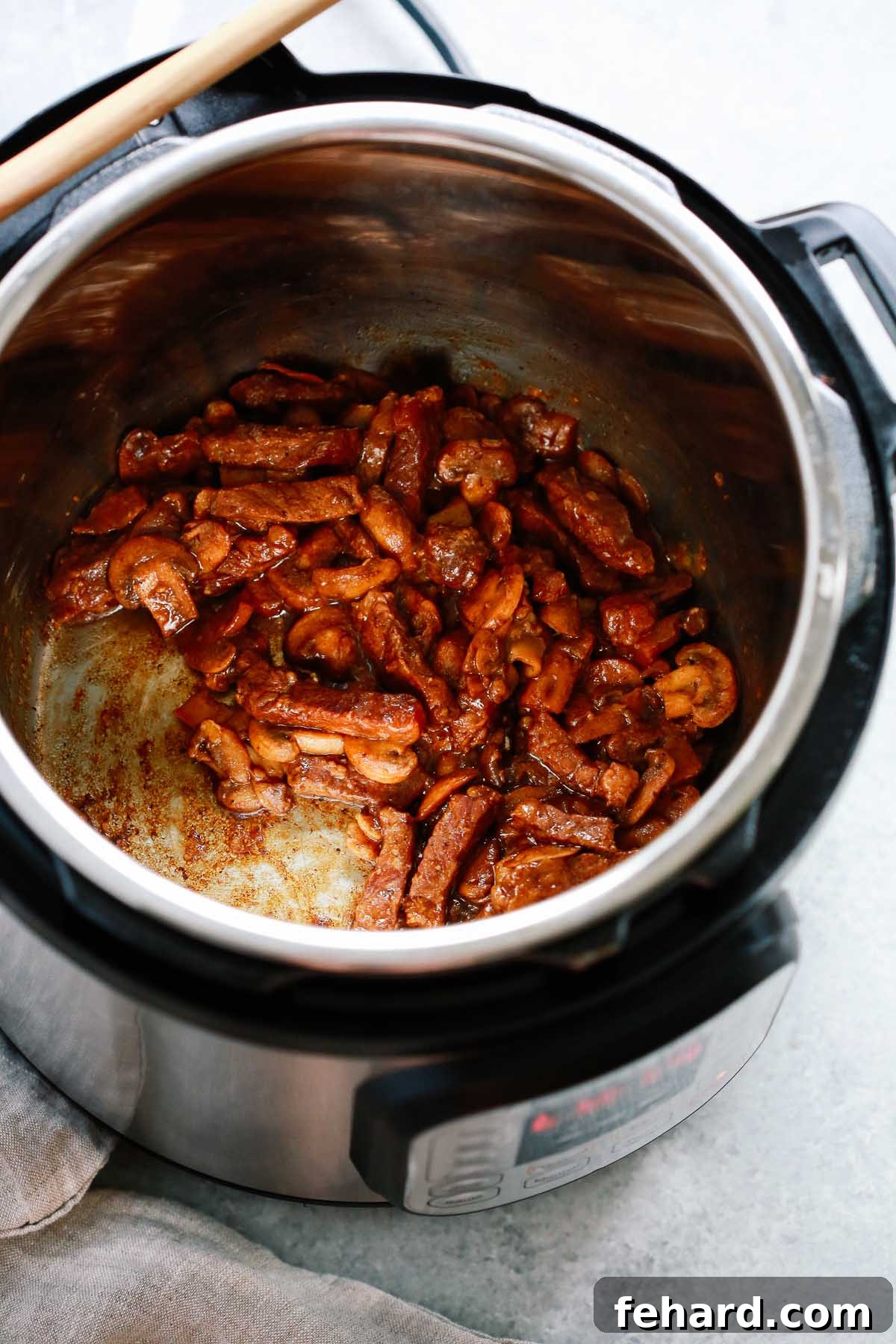 Instant Pot with cooked sirloin steak and mushrooms generously coated in a rich, thick sauce