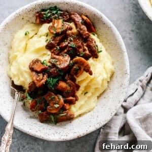 Bowl of mashed potatoes topped with steak and mushrooms