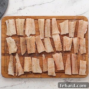 Seasoned fish sticks on wooden cutting boards.