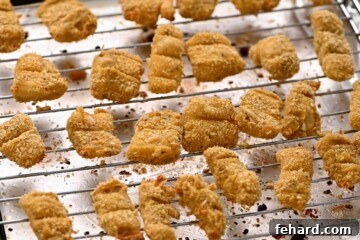 Baked fish sticks on baking rack over baking sheets.