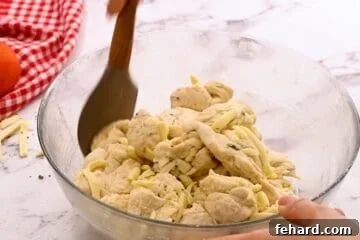 Spatula gently tossing pizza dough with cheese and pizza seasonings.