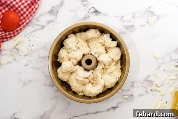 Cheesy pizza dough layered in greased bundt cake pan before rising to make pizza bread.