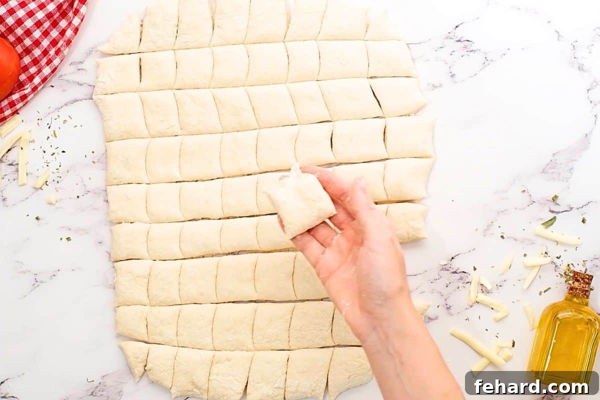 Pizza dough rolled out on a floured surface, precisely cut into 1-inch cubes.