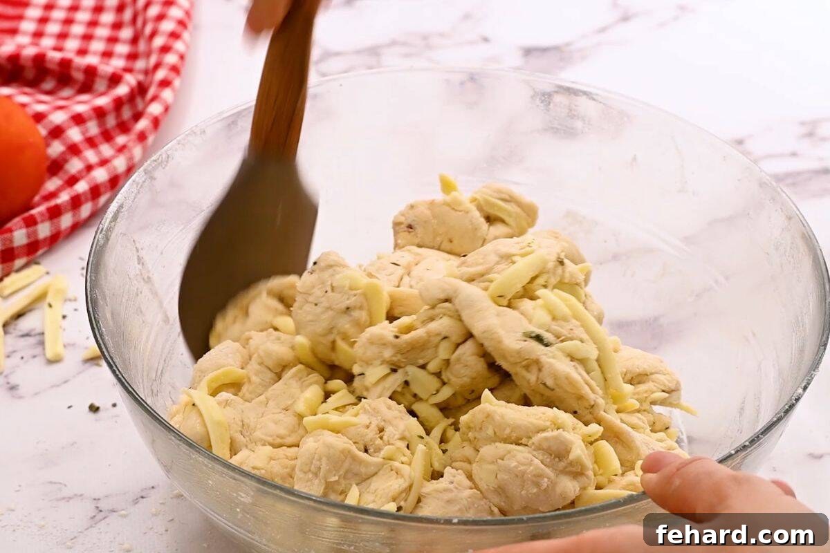 Spatula gently tossing pizza dough with a rich blend of cheeses and pizza seasonings.