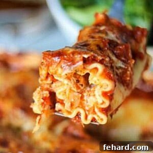 Lasagna Roll being taken out of baking dish, showcasing its cheesy topping.