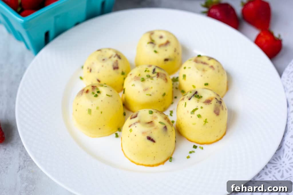 Three perfectly cooked Instant Pot Egg Bites arranged on a white plate, garnished with fresh berries, ready for a delicious breakfast.