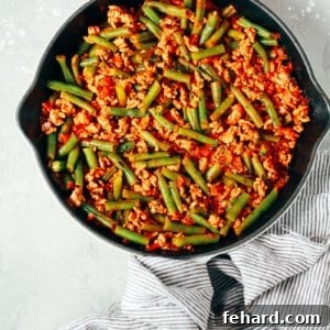 overhead view of a white skillet containing green beans and ground turkey