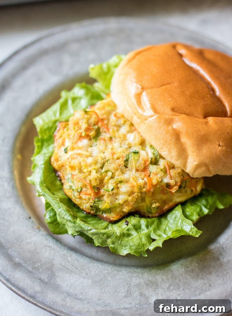 Savory Quinoa Burger on a toasted bun with crisp lettuce and a slice of tomato, served on a modern silver plate.