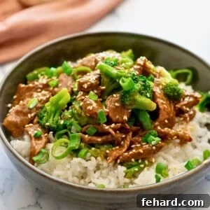 Instant Pot Beef and Broccoli served over white rice and topped with sesame seeds and sliced green onions.
