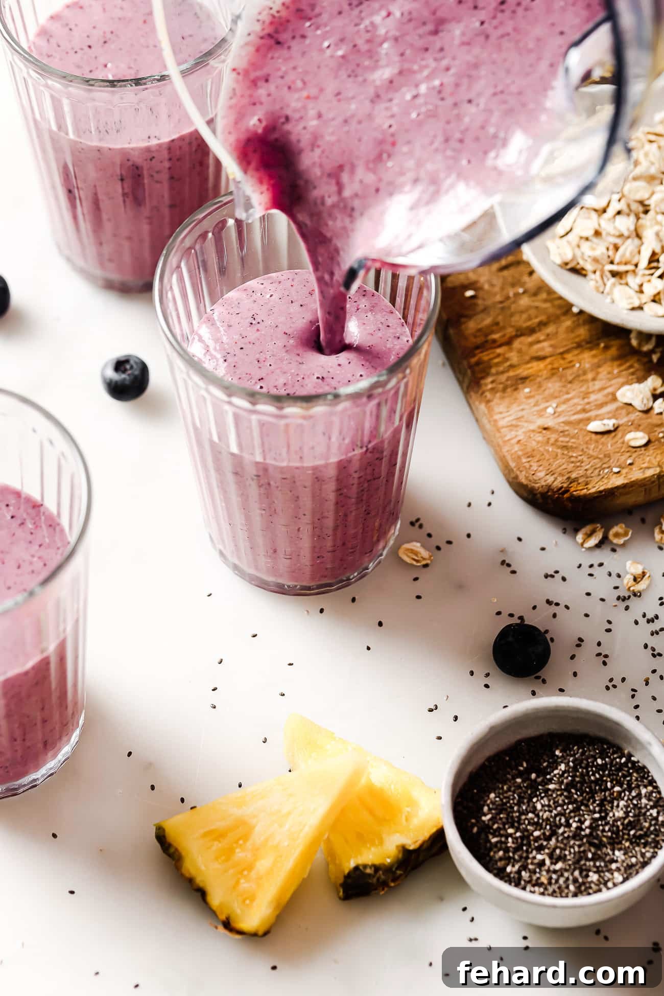 Pouring a vibrant purple blueberry banana smoothie from the blender into a tall glass, ready to be enjoyed.