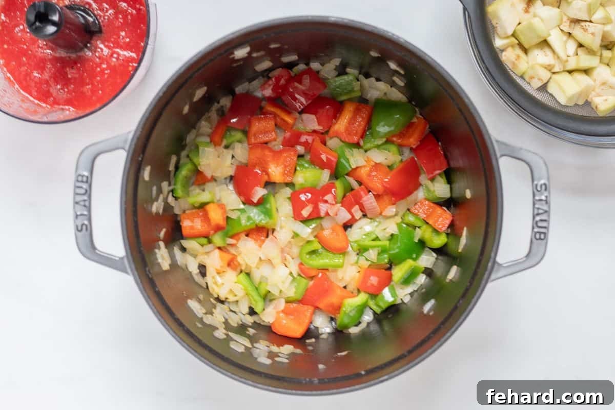 Sauteed onion, bell peppers, and fresh herbs in a large stock pot, filling the kitchen with inviting aromas.