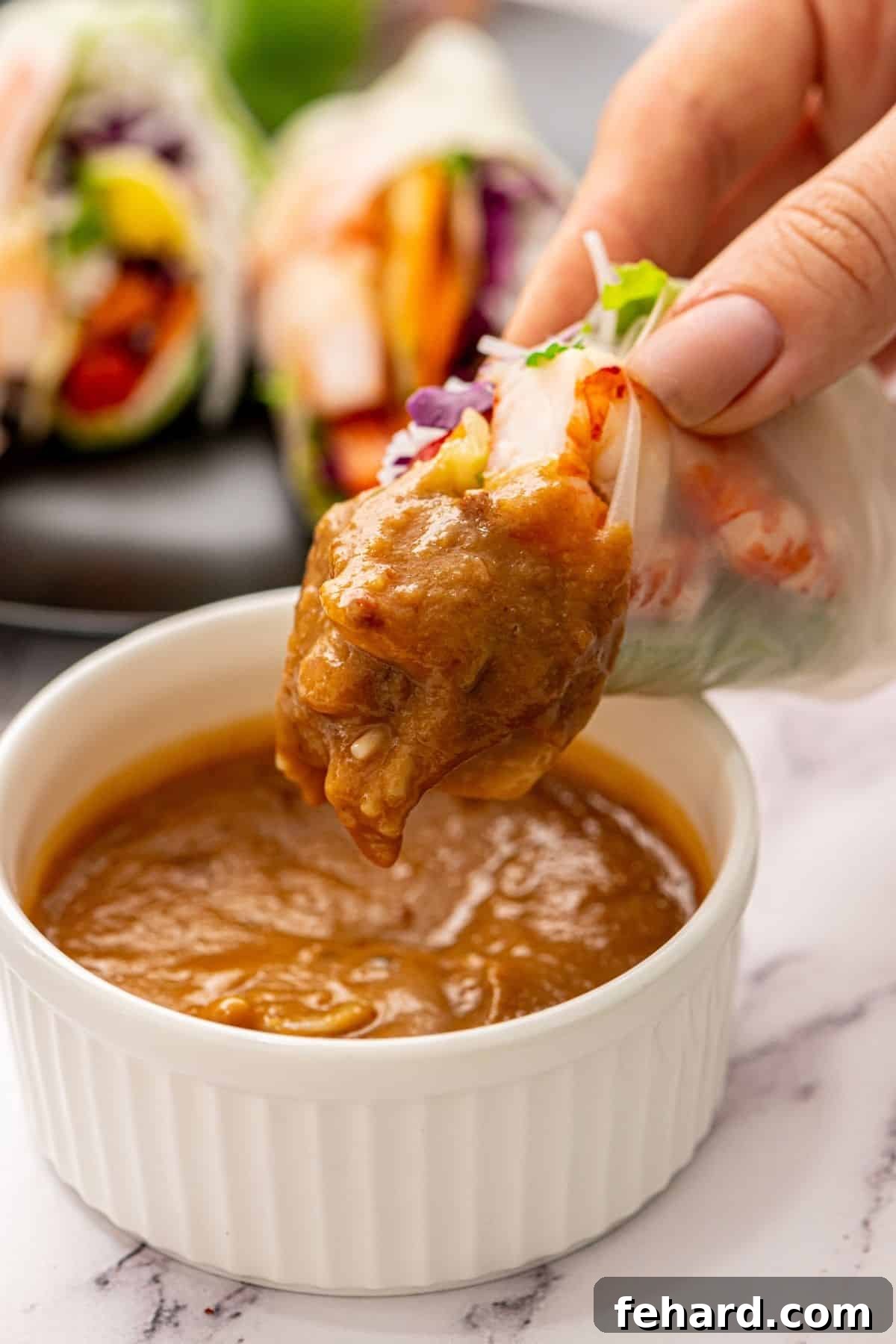 Delicious Homemade Spring Rolls with Dipping Sauce Fresh Spring Roll dipped into Asian Peanut Sauce, ready to be enjoyed.