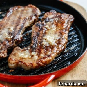 cooked steaks with garlic butter in a skillet on a cutting board